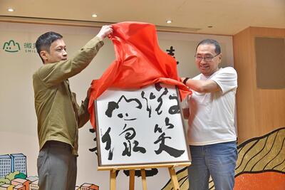 新北市政府邀請台灣知名青年書法藝術家徐經綸(左)為「微笑山線」服務據點設計識別牌